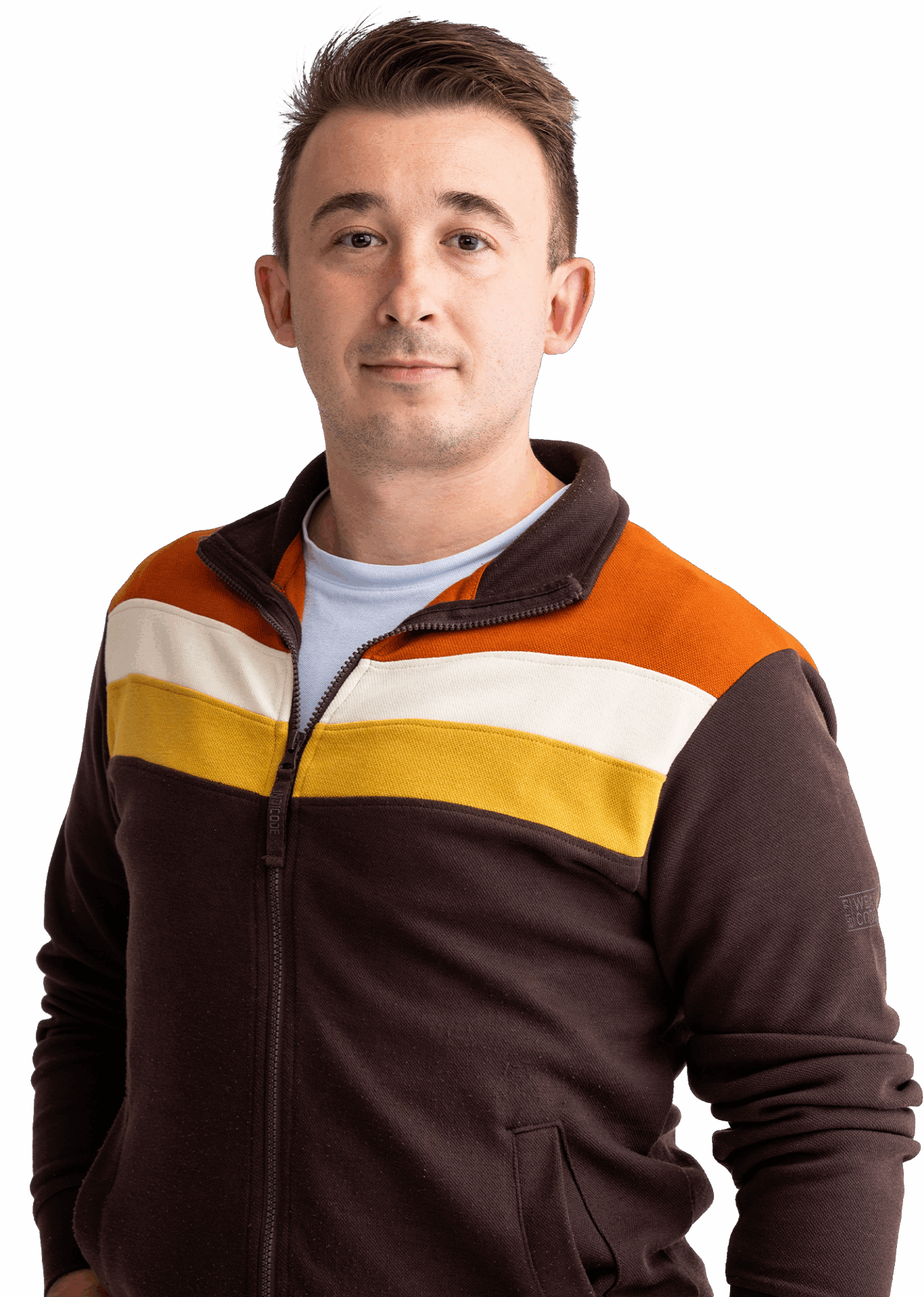 Portrait von Nikola Jurišić in einem weißen Shirt, brauner Sweatjacke mit orange-weiß-gelben Streifen; er hat kurzes braunes Haar und lächelt leicht.