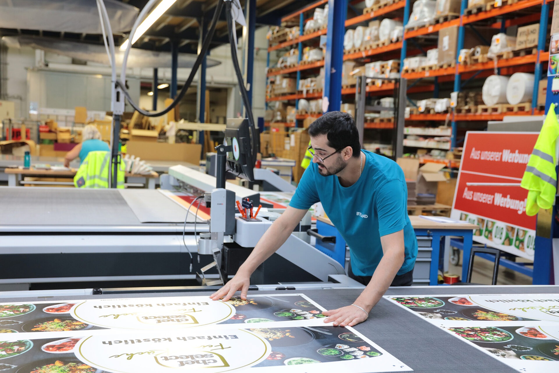 IFFLAND Mitarbeiter in der Weiterverarbeitung kontrolliert die korrekte Platzierung von Bannern auf dem Schneideuntergrund.